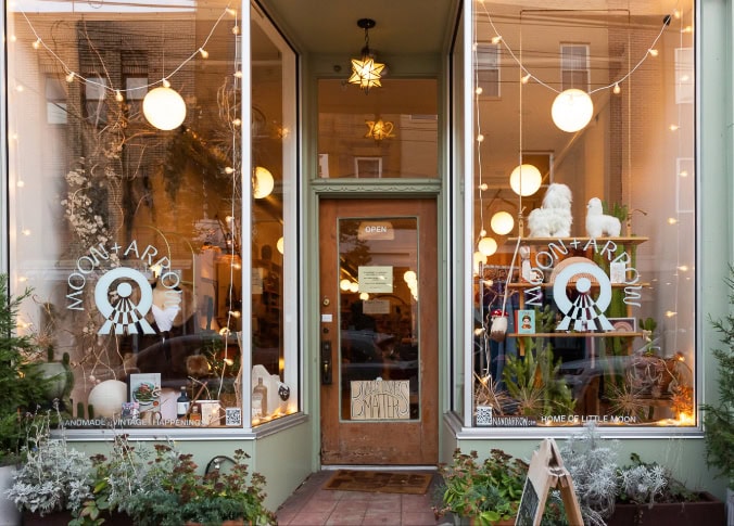 Front view of a storefront named Moon + Arrow with large windows displaying various items and a hanging star-shaped light above the door.