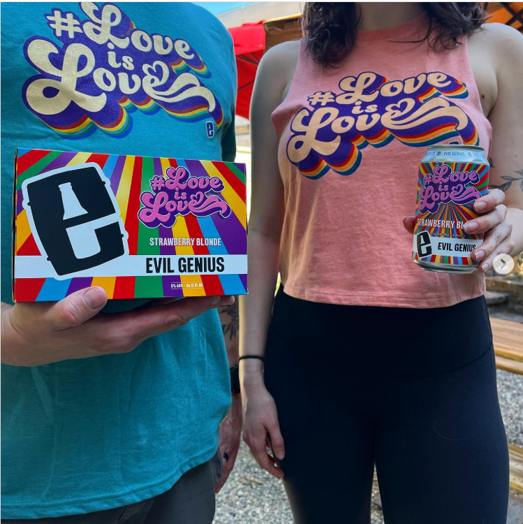 Two people wearing “#Love is Love” shirts hold an Evil Genius Strawberry Blonde beer can and matching box with colorful rainbow-themed packaging.